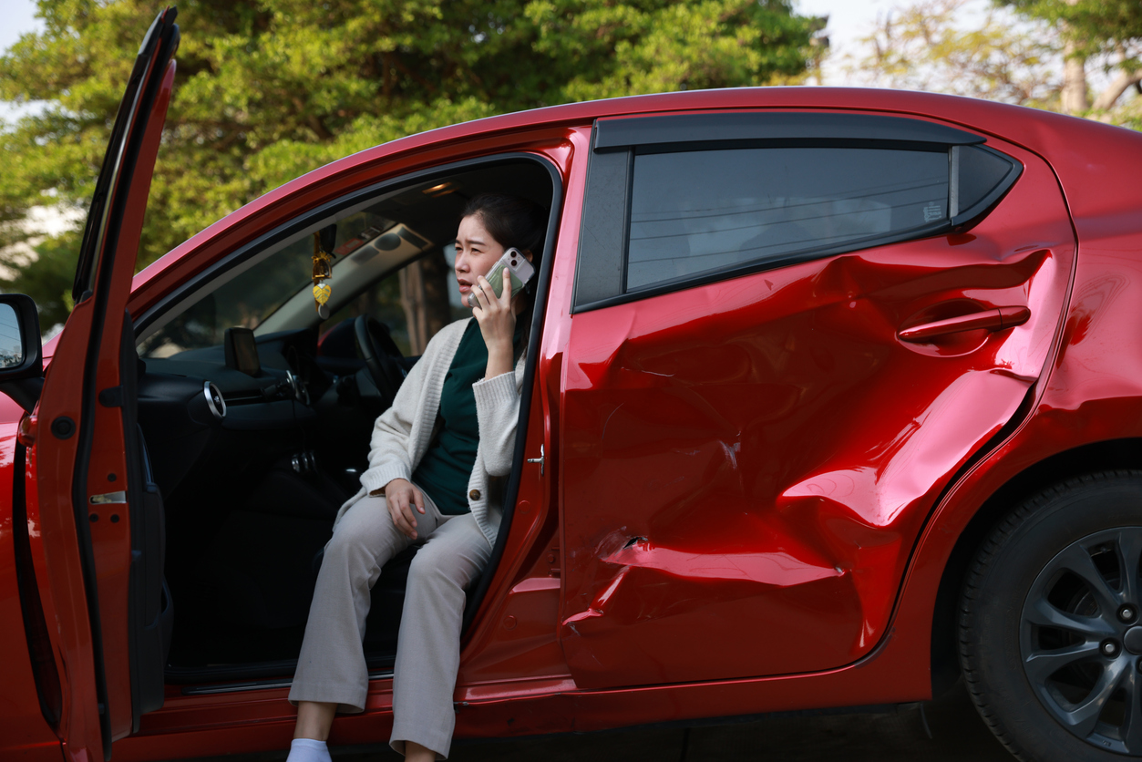 A female motorist is sitting in her car on the side of the road after a car accident