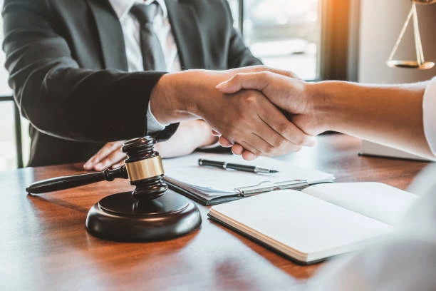 An attorney shakes the hand of a client over their desk.