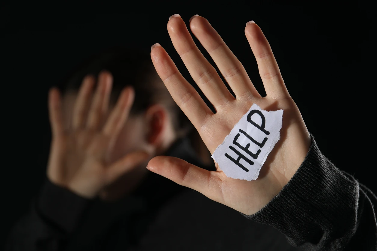 Woman holding piece of paper with word Help on black background, closeup.