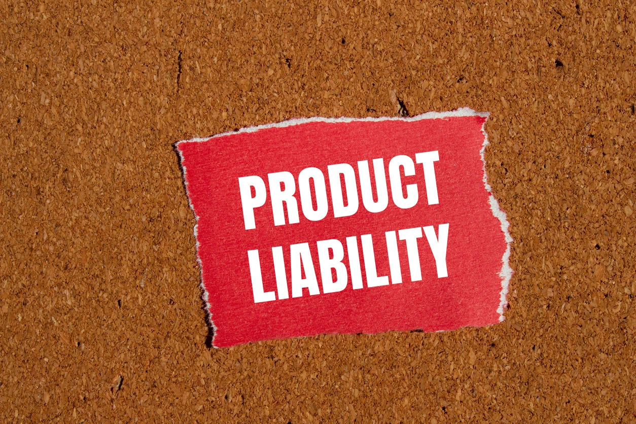 Product liability words written on ripped red paper piece with brown background.